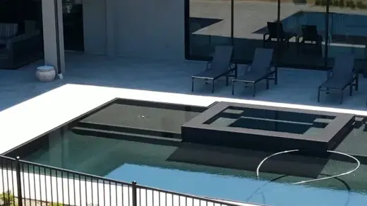 Pool with hot tub in the middle outside a modern house